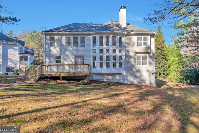 rear view of house featuring a wooden deck and a lawn