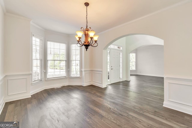 empty room featuring crown molding, dark hardwood / wood-style floors, and a notable chandelier