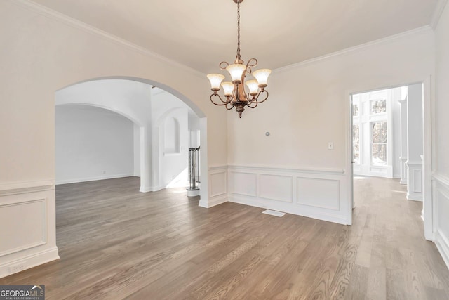 unfurnished dining area with hardwood / wood-style flooring, ornamental molding, and a chandelier