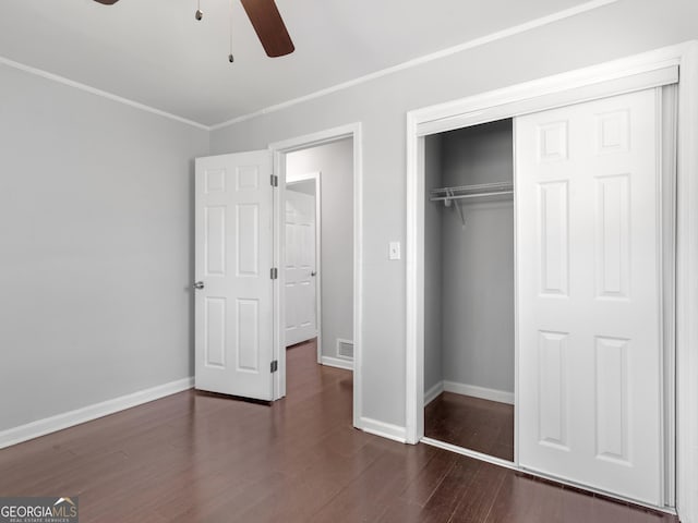 unfurnished bedroom featuring crown molding, ceiling fan, dark hardwood / wood-style flooring, and a closet