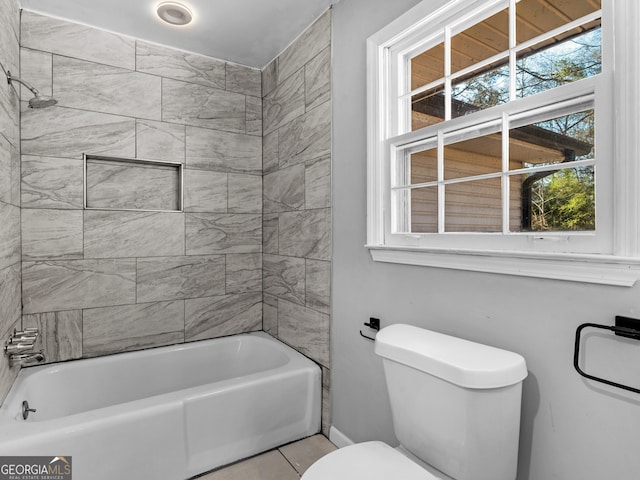 bathroom featuring tiled shower / bath combo, tile patterned floors, and toilet