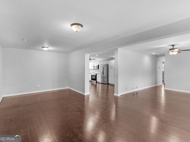 unfurnished living room featuring dark wood-type flooring and ceiling fan