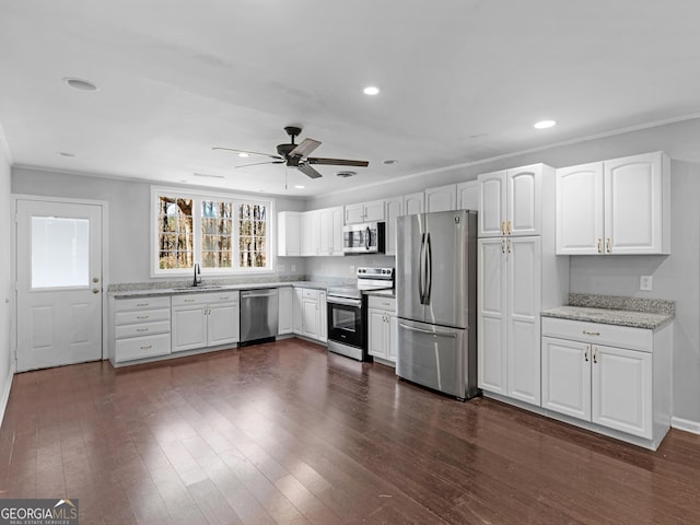 kitchen featuring sink, dark wood-type flooring, white cabinetry, stainless steel appliances, and light stone counters