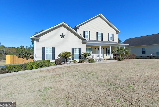 view of property featuring covered porch and a front yard