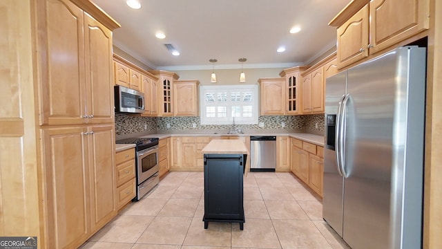 kitchen featuring crown molding, stainless steel appliances, a kitchen island, and light brown cabinets