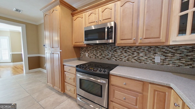 kitchen with light brown cabinetry, crown molding, light tile patterned floors, stainless steel appliances, and backsplash