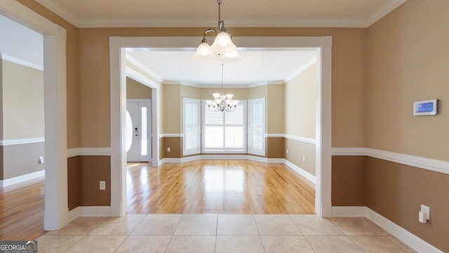 unfurnished dining area featuring ornamental molding, light tile patterned floors, and an inviting chandelier