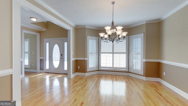 entryway with ornamental molding, a chandelier, and light hardwood / wood-style flooring