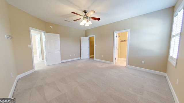 unfurnished bedroom with ceiling fan, light colored carpet, and a walk in closet