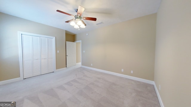 unfurnished bedroom featuring light colored carpet, ceiling fan, and a closet