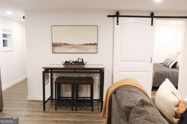 sitting room featuring wood-type flooring, a barn door, and ornamental molding