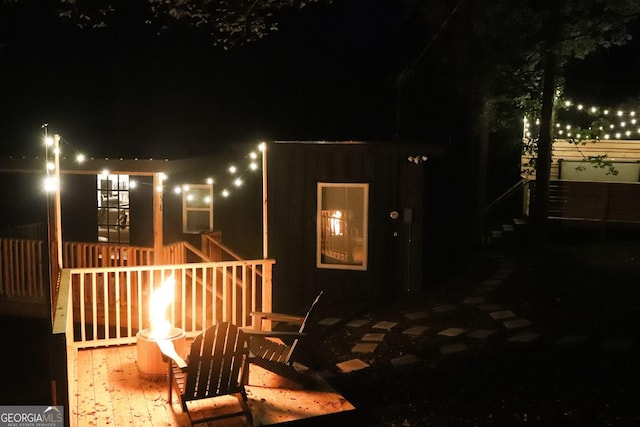 back house at night with a wooden deck and an outdoor fire pit