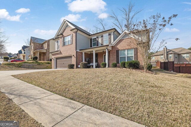 traditional home featuring fence, driveway, an attached garage, brick siding, and a residential view