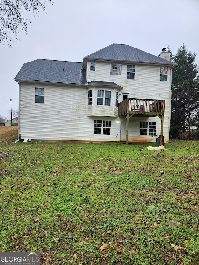 rear view of property featuring a yard and a deck