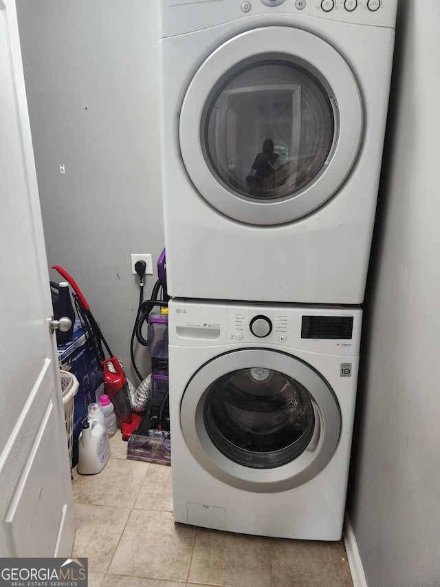 laundry area featuring stacked washer and dryer and light tile patterned floors