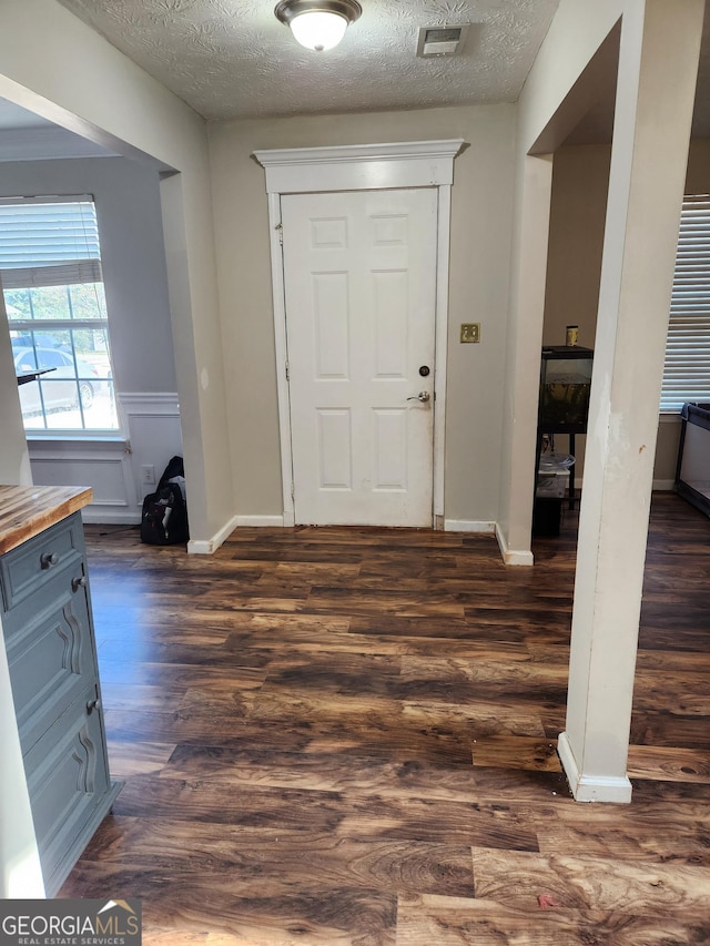 entryway featuring dark wood-type flooring and a textured ceiling