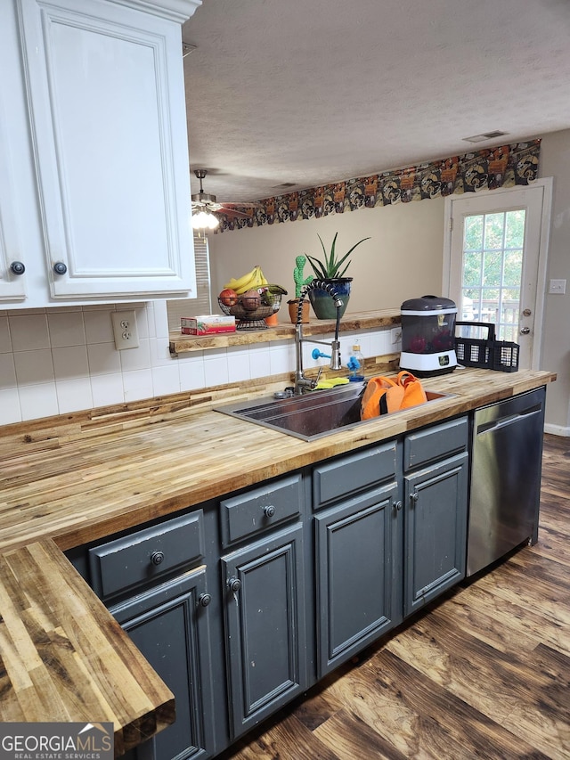 kitchen featuring white cabinetry, decorative backsplash, stainless steel dishwasher, and wooden counters