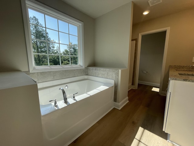 bathroom featuring vanity, hardwood / wood-style floors, and a washtub