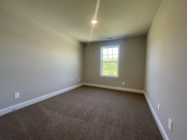 spare room featuring dark carpet