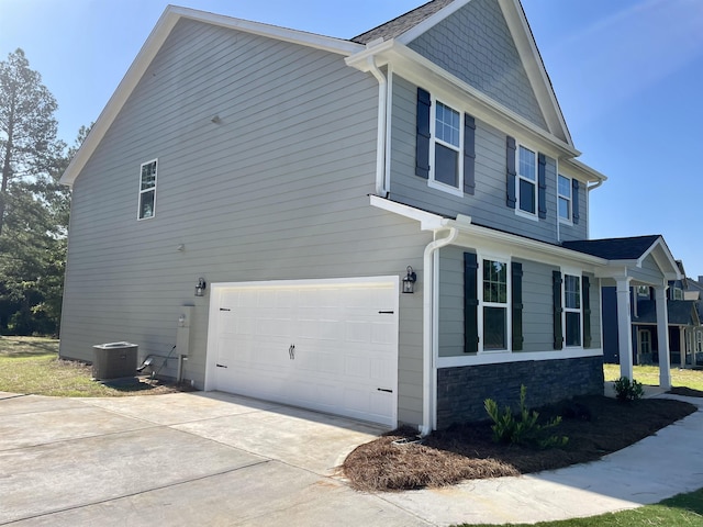 view of side of home featuring a garage and cooling unit