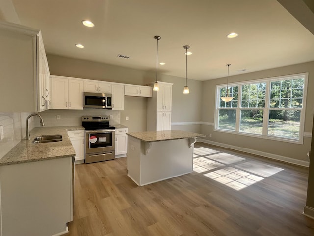 kitchen featuring sink, a kitchen island, white cabinets, stainless steel appliances, and backsplash