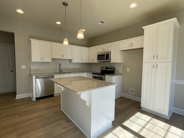 kitchen featuring sink, white cabinetry, light stone counters, a kitchen island, and stainless steel appliances