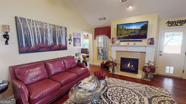 living room with hardwood / wood-style floors, a tile fireplace, and high vaulted ceiling