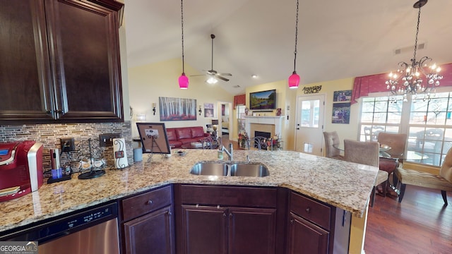 kitchen featuring vaulted ceiling, pendant lighting, tasteful backsplash, dishwasher, and sink