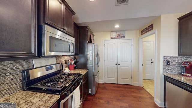 kitchen featuring stainless steel appliances, light stone countertops, backsplash, and dark brown cabinetry