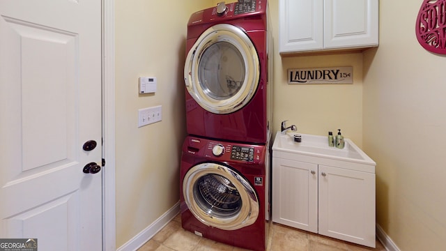 laundry room featuring cabinets, stacked washer / dryer, and sink