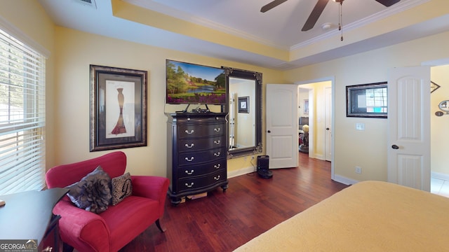 bedroom featuring a raised ceiling, dark hardwood / wood-style flooring, ceiling fan, and multiple windows