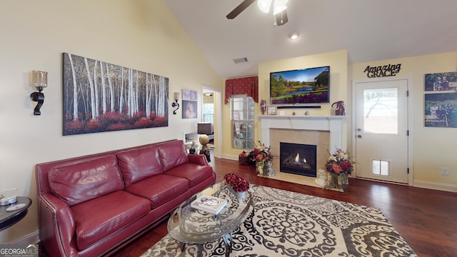 living room featuring hardwood / wood-style flooring, ceiling fan, lofted ceiling, and a tiled fireplace