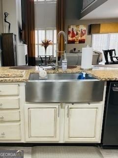 kitchen with sink, cream cabinets, light stone countertops, and dishwasher