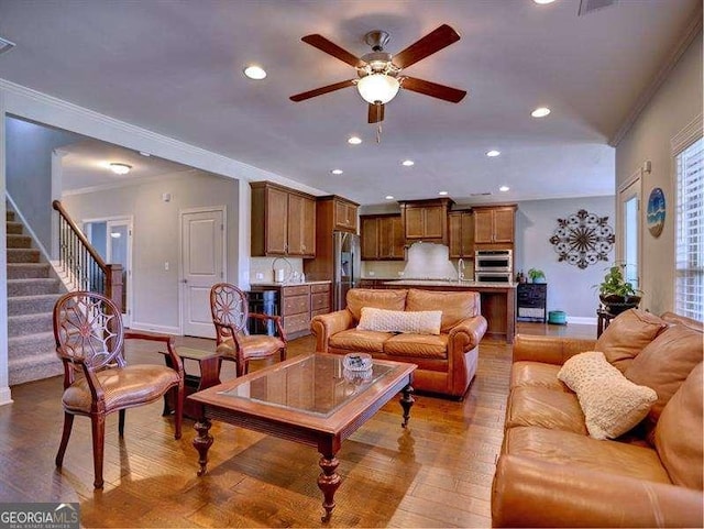 living room featuring hardwood / wood-style flooring, crown molding, sink, and ceiling fan