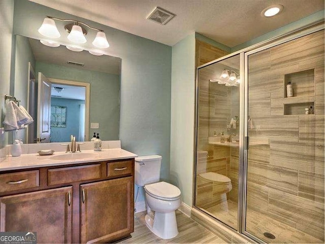 bathroom with walk in shower, vanity, and toilet