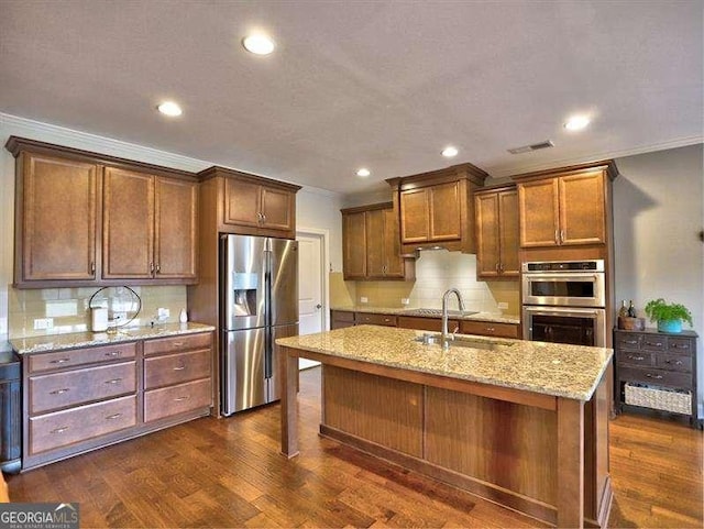 kitchen with sink, tasteful backsplash, a center island with sink, appliances with stainless steel finishes, and dark hardwood / wood-style flooring