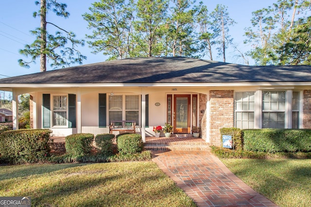 ranch-style home featuring a front lawn and covered porch