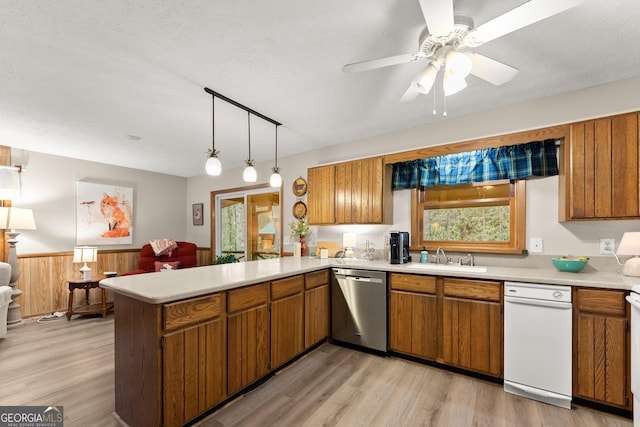 kitchen with wood walls, dishwasher, sink, kitchen peninsula, and a textured ceiling