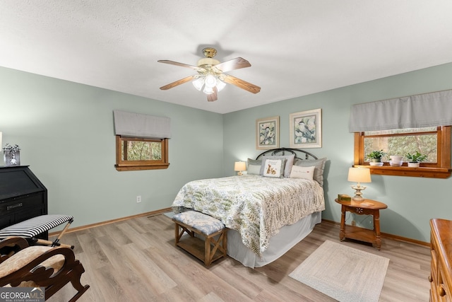 bedroom with a textured ceiling, light hardwood / wood-style flooring, and ceiling fan