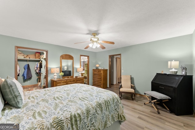 bedroom with ceiling fan, light hardwood / wood-style floors, a closet, and a textured ceiling