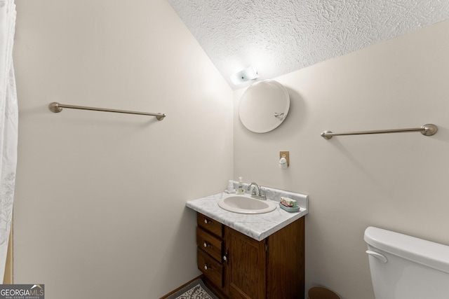 bathroom with vanity, toilet, and a textured ceiling