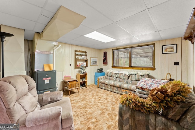 carpeted living room with a drop ceiling and wooden walls