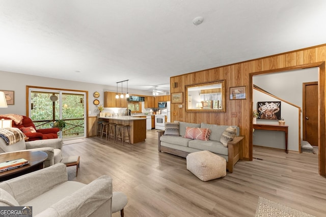 living room with light wood-type flooring, sink, and wood walls