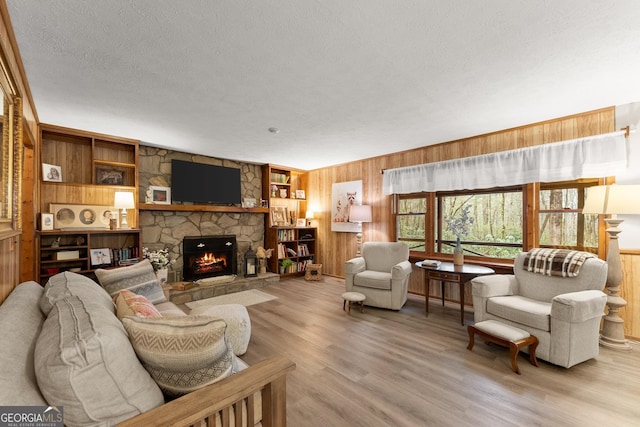 living room with wooden walls, a fireplace, and light wood-type flooring