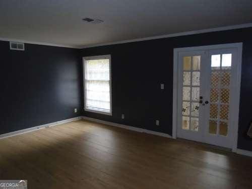 empty room featuring hardwood / wood-style flooring, crown molding, and french doors