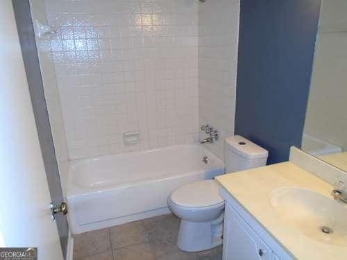 full bathroom featuring vanity, tile patterned flooring, tiled shower / bath combo, and toilet