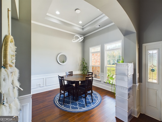 dining area featuring crown molding, a tray ceiling, and dark wood-type flooring