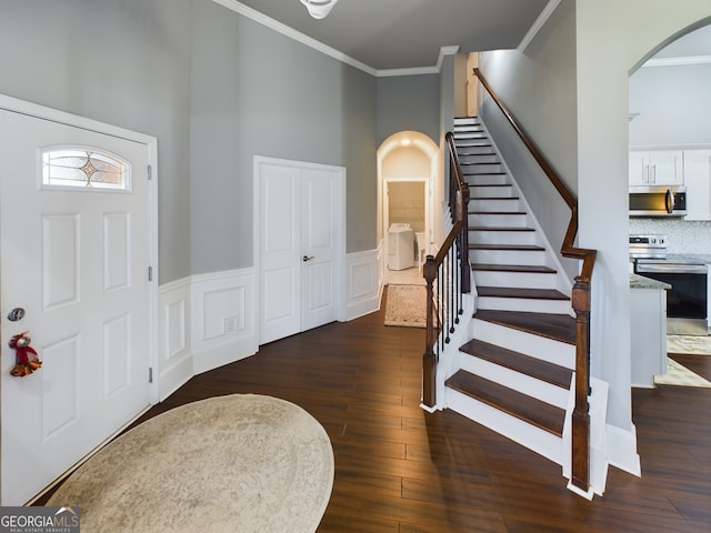 foyer entrance featuring crown molding, dark wood-type flooring, and a high ceiling