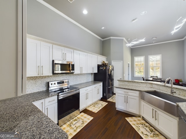 kitchen with white cabinetry, appliances with stainless steel finishes, sink, and dark stone counters