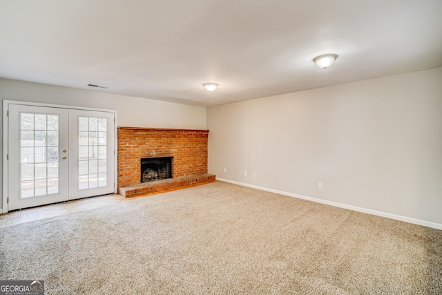 unfurnished living room with carpet, a fireplace, and french doors